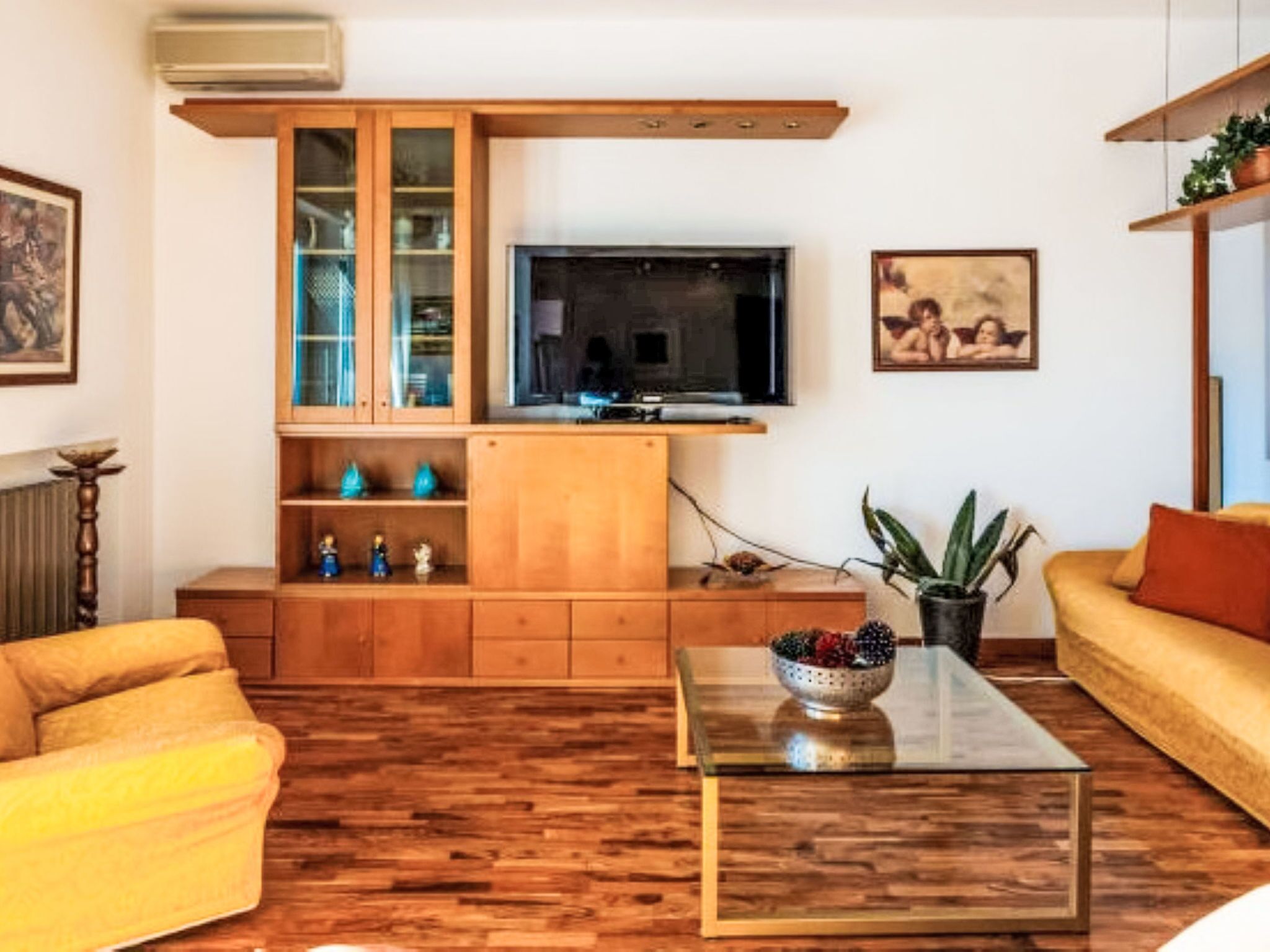 A living room with a wooden cabinet, a television, a sofa, and a coffee table.