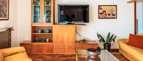 Una sala de estar con un aparador de madera, un televisor, un sofá y una mesa de centro.