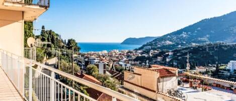 A balcony with a view of a coastal town and a mountain.