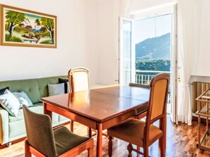 Ein Zimmer mit einem Holzesstisch, Stühlen, einem grünen Sofa und einem Bild an der Wand.