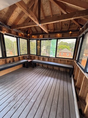 Eine hölzerne Veranda mit Bänken und großen Fenstern.