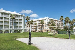 Ein Hotel mit mehreren Balkonen, einem gepflegten Rasen und blauem Himmel.