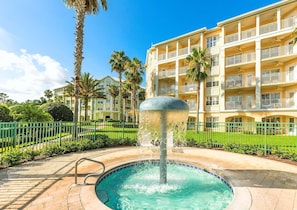 Ein Hotel mit Swimmingpool, Palmen und einem mehrstöckigen Gebäude mit Balkonen.