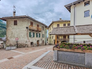 A cobblestone street with historic buildings, a no parking sign, and a flower bed. - La Fiamma by Interhome (Pellizzano)
