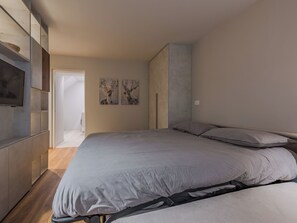 Een slaapkamer met een bed, een kledingkast en twee aan de muur hangende schilderijen.