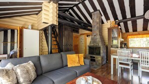 A cozy living room with a sofa, a wooden table with candles, and a fireplace. - Villa Succa (Kittilä)