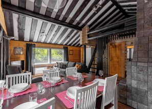 A cozy cabin interior with a dining area, wooden walls, a fireplace, and a staircase. - Villa Succa (Kittilä)