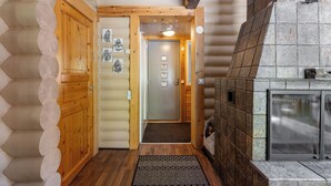 A log cabin interior with a wooden staircase, a fireplace, and a door leading to another room. - Villa Succa (Kittilä)