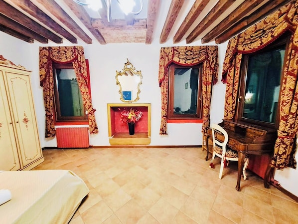 Una stanza con soffitto in legno, uno specchio, un camino, un armadio in legno e una poltrona.
