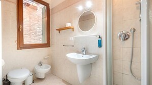Un bagno con WC, bidet, lavandino, specchio e doccia.