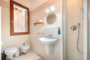 A bathroom with a toilet, bidet, sink, mirror, and shower. - Venezia Baroque Charm (Venice)
