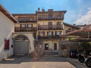 Ein zweistöckiges Gebäude mit Balkon und Garage, vor der ein Motorrad geparkt ist.