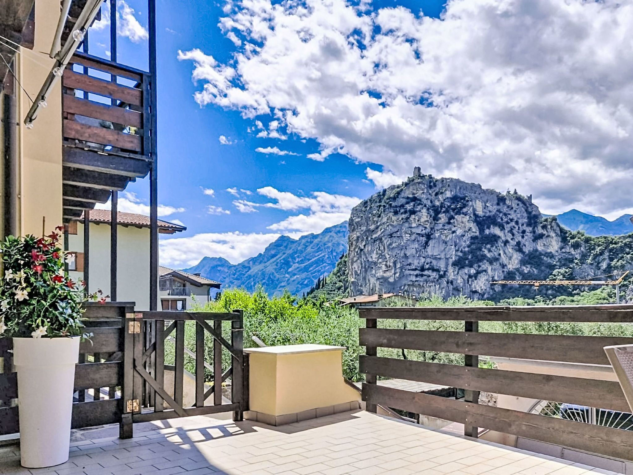 Un balcón con vistas a montañas, una valla de madera y una planta en maceta.