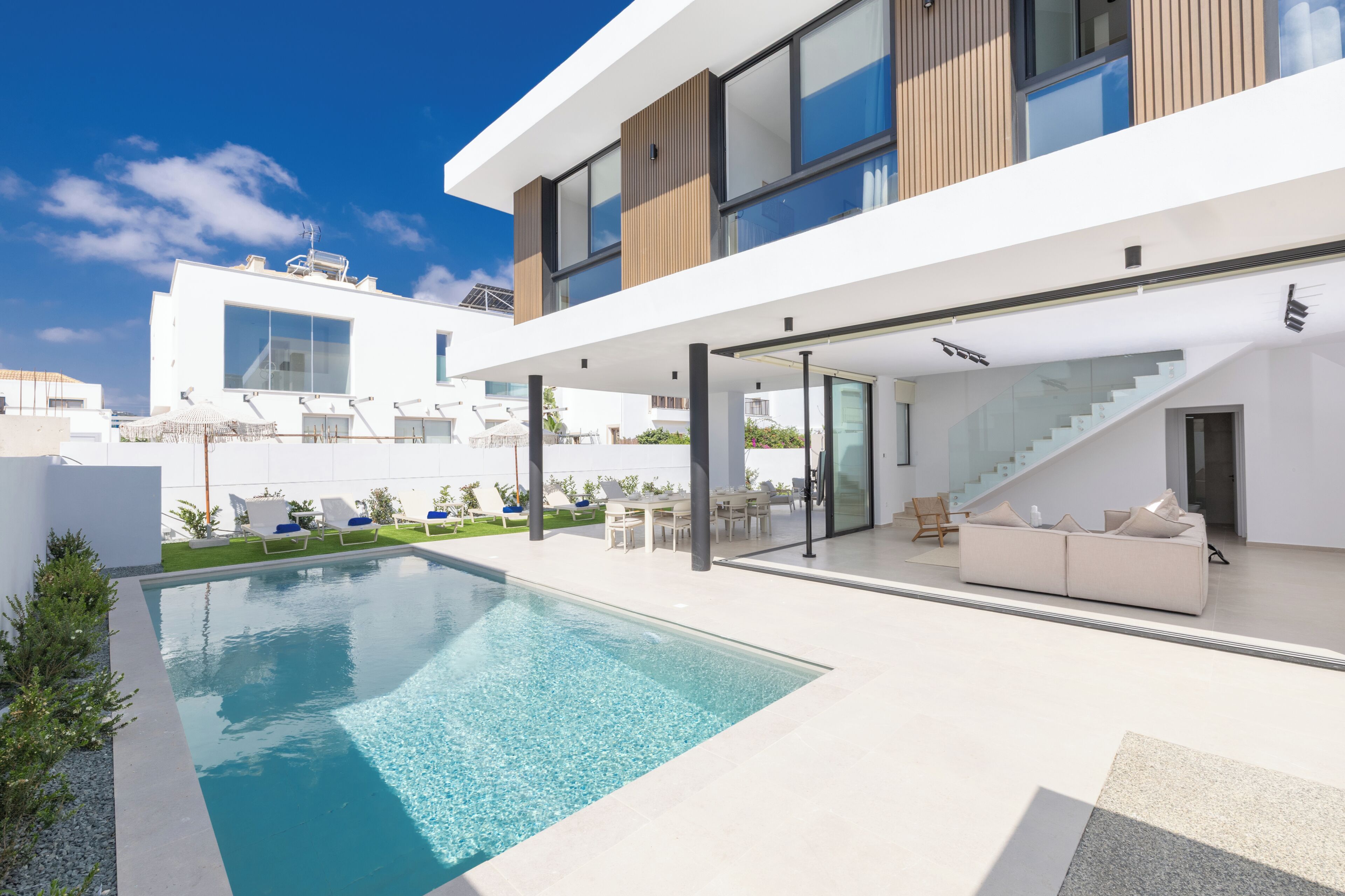 Une maison moderne dotée d’une piscine, d’un espace salon extérieur et d’un escalier.