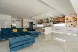 A modern kitchen with white cabinets, a central island, and a bar area.