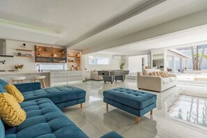A spacious living area with a blue sofa, a beige sofa, and a dining table.