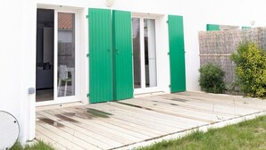 Ein weißes Gebäude mit grünen Fensterläden, einer Holzterrasse und einem Rasen.