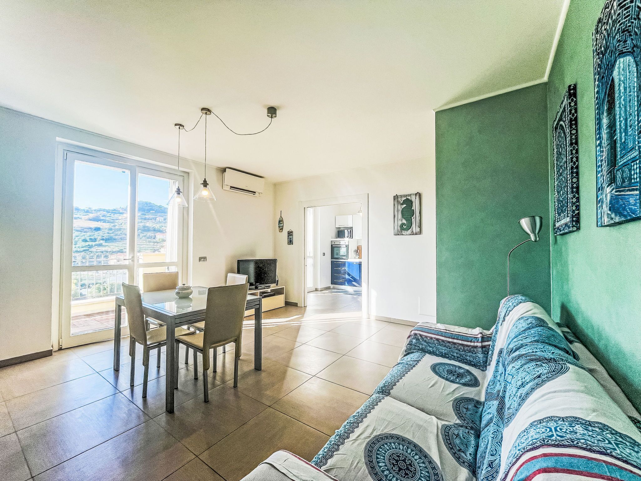 Un amplio espacio de estar con una mesa de comedor, sillas, un sofá y una cocina al fondo.