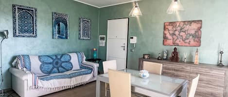 A compact living space with a sofa, dining table, chairs, a cabinet, and decorative wall art.