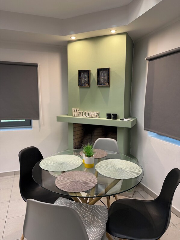 Una sala de reuniones moderna con una mesa de vidrio, sillas negras y grises, un cartel de bienvenida y una pequeña planta en maceta.