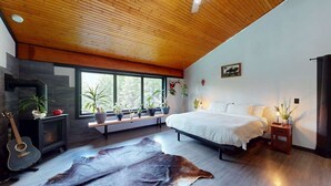 Une chambre à coucher avec un lit, une guitare, une cheminée et une grande fenêtre.