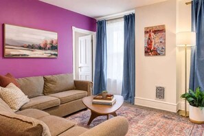 A living room with a sofa, a coffee table, a painting, and a lamp. - Fifa Stay Walk Manayunk River 4 Beds Sleeps 6 (Philadelphia)