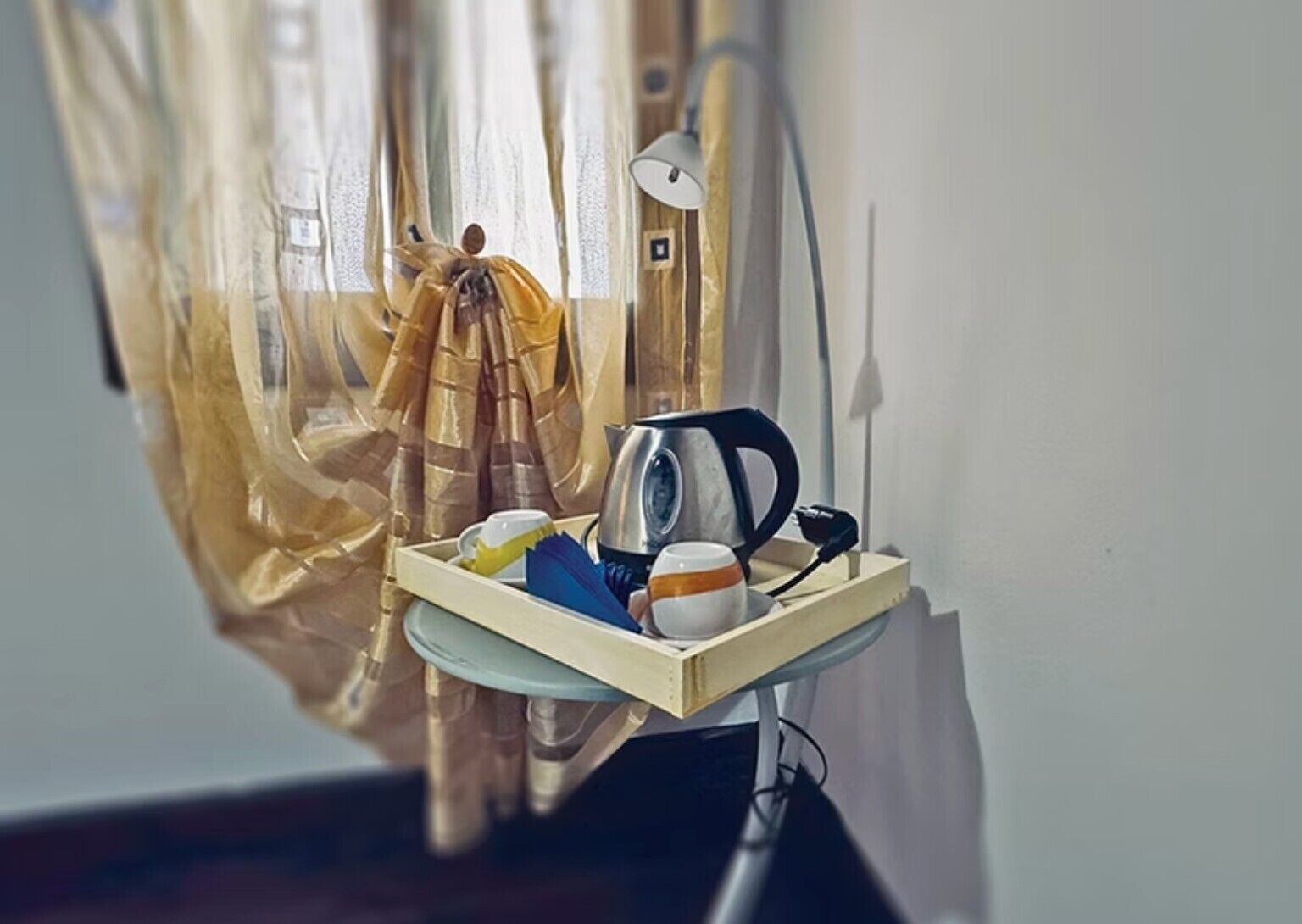 Une petite table avec une bouilloire, une tasse et un plateau.