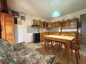 A compact kitchen with wooden cabinets, a dining table, and a sofa. - La Dimora di Artemide (Chiaramonte Gulfi)