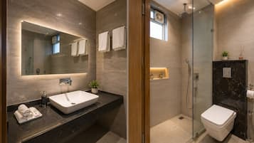 A modern bathroom with a large mirror, a sink, a toilet, and a shower area.