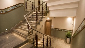 A multi-level interior with a central staircase, a wooden door, and a potted plant. - Hotel Salt and Rove Near Delhi Airport (New Delhi)