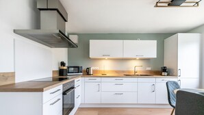 Una cucina moderna con pensili bianchi, un forno a microonde, un bollitore e una macchina da caffè.