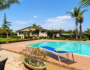 Ein Swimmingpool mit Liegestuhl und Topfpflanze.