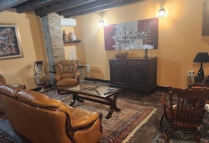 Una sala de estar con sofás de cuero, una mesa de centro, chimenea, pared de piedra y un cuadro en la pared.