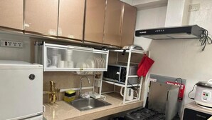 Une cuisine équipée d’un réfrigérateur GE, d’un égouttoir à vaisselle, d’une cuisinière et d’une hotte aspirante.