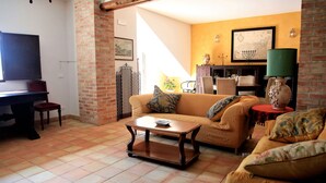 Ein Wohnzimmer mit einer Couch, einem Couchtisch, einem Fernseher und einer Ziegelwand.
