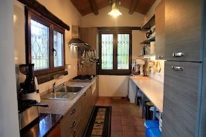 Eine Küche mit Herd, Spüle und Kühlschrank, Holzschränken und einem Fenster mit Blick.