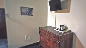 Una stanza con un comò in legno, una TV a schermo piatto montata a parete e un quadro incorniciato.