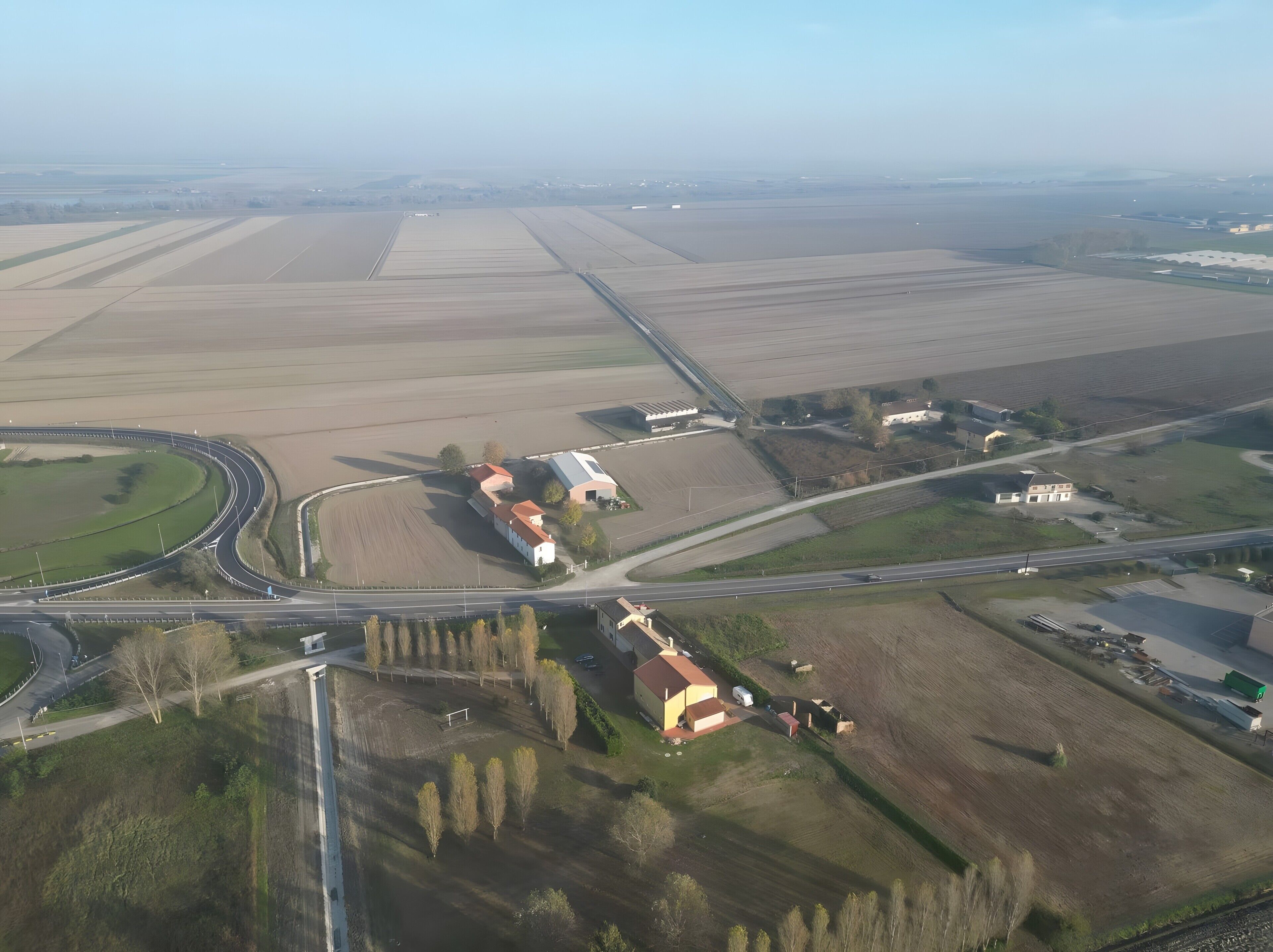 Eine Vogelperspektive auf eine ländliche Gegend mit Feldern, einer Straße und einigen Gebäuden.