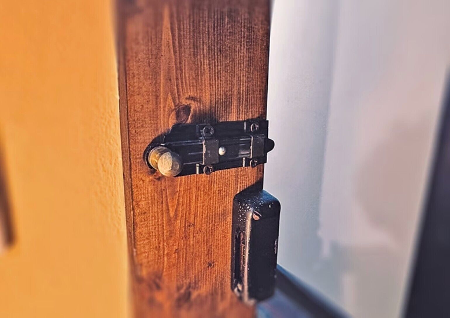Une porte en bois avec un loquet métallique et une poignée de porte ronde.