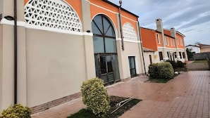 A building with a beige facade, large arched windows, and a brick pathway. - 'Picchio' Room with Wi-Fi and Air Conditioning (Taglio di Po)