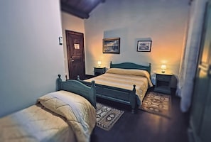 Een slaapkamer met twee eenpersoonsbedden, een houten deur en twee nachtkastjes met lampen.