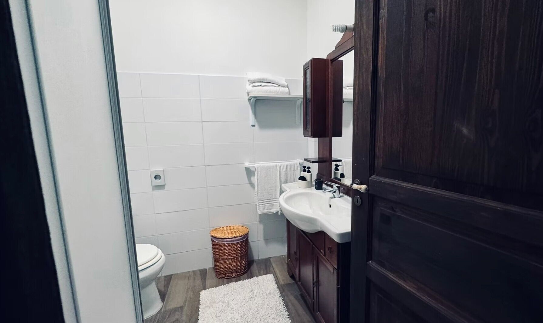 Ein Badezimmer mit Toilette, Waschbecken, Spiegel und einem Korbwannenaufsatz.