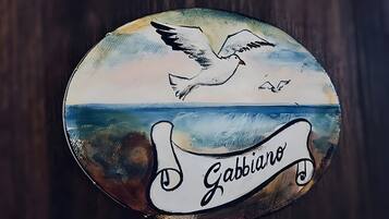 Un letrero circular con un ave y olas, y el texto 'Gabbiano'.
