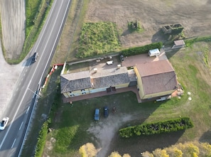 Luchtbeeld van een gebouw met een schuin dak, naast een weg met voertuigen.