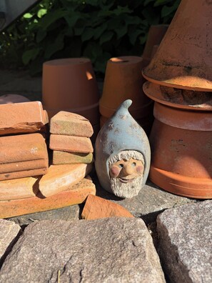 Terracotta planters and a gnome figurine on a stone surface.