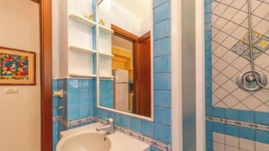 Een badkamer met een wastafel, spiegel en blauwe betegelde wanden.