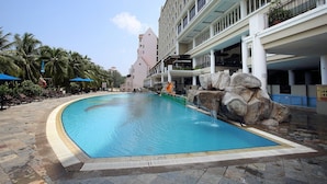 A hotel pool with a clear blue water feature, palm trees, and a large rock formation. - Portrait Resort Port Dickson (Port Dickson)