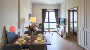 A modern hotel room with a dining area, a TV, and a view of the outdoors. - Portrait Resort Port Dickson (Port Dickson)