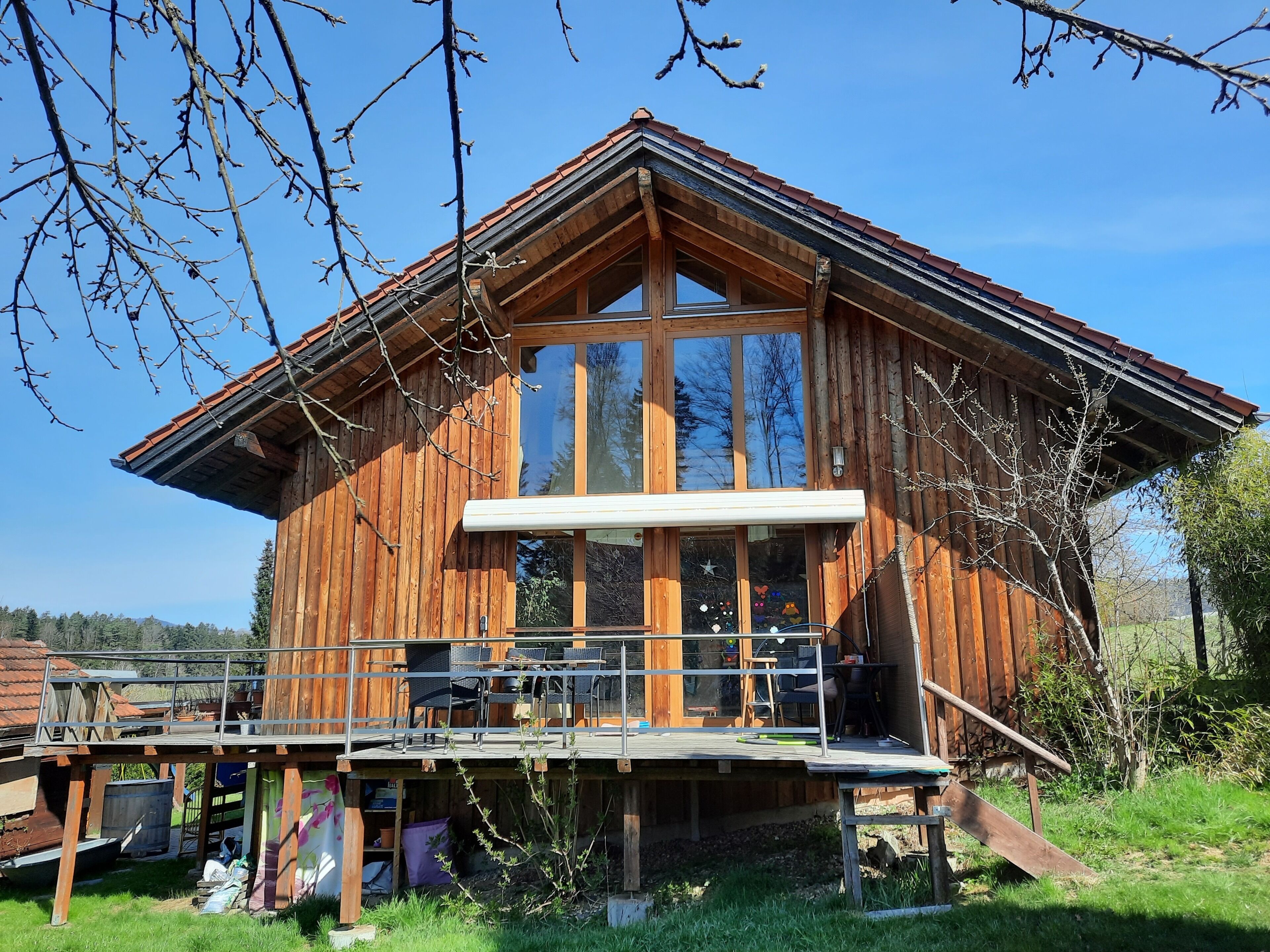 Eine Holzhütte mit Balkon, großen Fenstern und Blick auf die umliegende Landschaft.