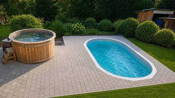 Ein rechteckiger Pool mit einer Holztonne und einer Pflasterterrasse.